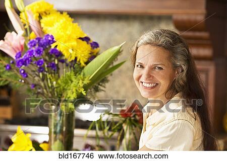 Stock Photograph - Hispanic woman with flowers in kitchen. Fotosearch
