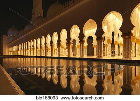 Stock Image - Illuminated colonnade reflecting in still pool. Fotosearch