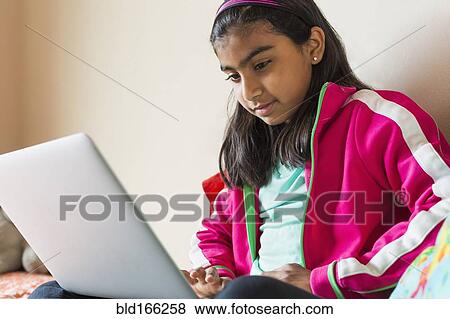 Stock Photo - Indian girl using laptop on bed. Fotosearch