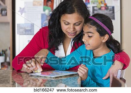 Indian mother and daughter using digital tablet at counter View Large Photo Image Stock Photo - Indian mother and daughter using digital tablet at counter. Fotosearch