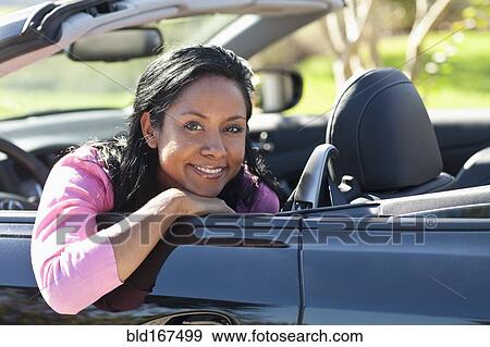 Stock Photo - Indian woman smiling in convertible. Fotosearch