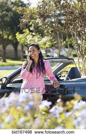 Stock Photo - Indian woman talking on cell phone near car. Fotosearch