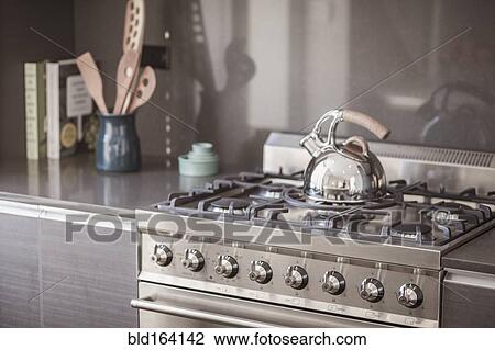 Stock Image - Kettle on stainless steel stove in modern kitchen. Fotosearch