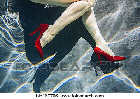 Stock Photograph - Legs of woman wearing high heels in swimming pool. Fotosearch