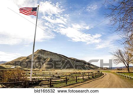 Stock Image - Low angle view of American flag over dirt road, Painted Hills, Oregon, United States. Fotosearch