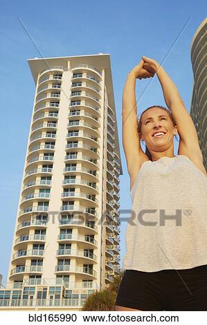 Low angle view of athlete stretching in city View Large Photo Image Stock Image - Low angle view of athlete stretching in city. Fotosearch