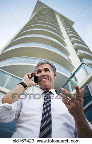 Low angle view of Caucasian businessman using cell phone at high rise building View Large Photo Image Stock Image - Low angle view of Caucasian businessman using cell phone at high rise building. Fotosearch