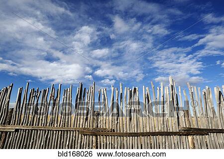 Stock Photograph - Low angle view of rustic corral fence under blue sky. Fotosearch