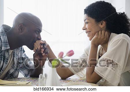 Picture - Man kissing hand of girlfriend at restaurant table. Fotosearch