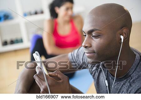 Stock Photo - Man listening to earphones in gym. Fotosearch