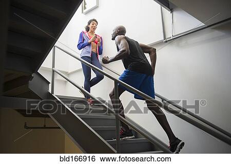 Stock Photograph - Man running with trainer on staircase. Fotosearch