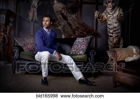 Stock Photo - Man sitting in parlor with stuffed animals. Fotosearch
