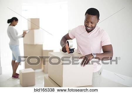 Man taping cardboard box to move View Large Photo Image Stock Photo - Man taping cardboard box to move. Fotosearch
