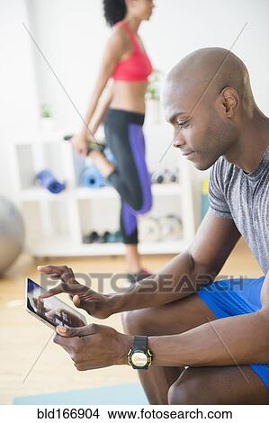 Man using digital tablet in gym View Large Photo Image Picture - Man using digital tablet in gym. Fotosearch