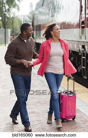 Stock Image - Man walking girlfriend to train at station. Fotosearch