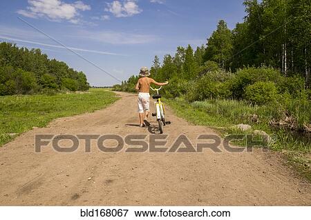 Mari boy walking bicycle on dirt path View Large Photo Image Stock Photo - Mari boy walking bicycle on dirt path. Fotosearch