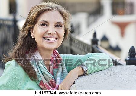 Picture - Middle Eastern woman leaning on gate. Fotosearch