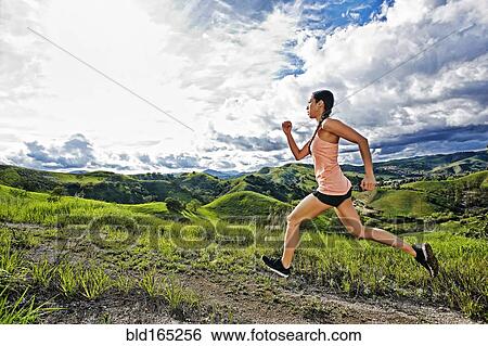Stock Photograph - Mixed race athlete running on rural hilltop. Fotosearch