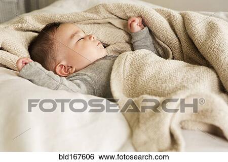 Stock Photograph - Mixed race baby sleeping in bed. Fotosearch