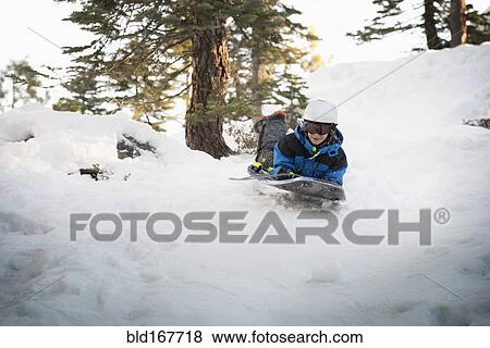 Mixed race boy sledding on snowy hillside View Large Photo Image Stock Photo - Mixed race boy sledding on snowy hillside. Fotosearch