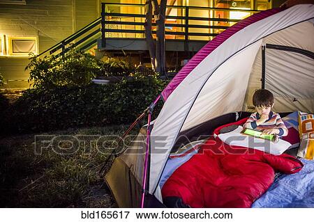 Mixed race boy using digital tablet in backyard tent View Large Photo Image Stock Photo - Mixed race boy using digital tablet in backyard tent. Fotosearch