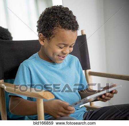 Stock Photo - Mixed race boy using digital tablet in directors s chair. Fotosearch