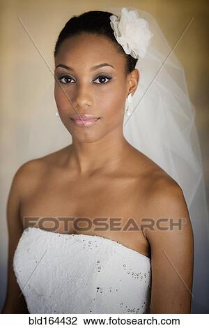 Stock Image - Mixed race bride wearing wedding gown and veil. Fotosearch