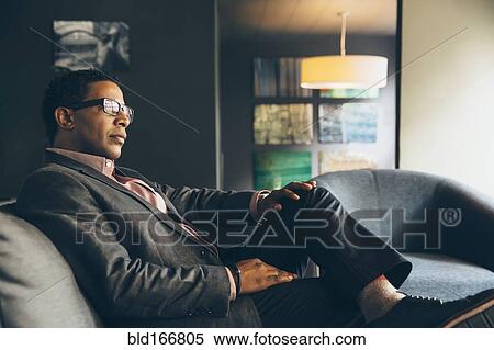Stock Photography - Mixed race businessman sitting in office lobby. Fotosearch
