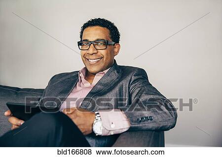 Mixed race businessman using digital tablet on sofa View Large Photo Image Stock Photo - Mixed race businessman using digital tablet on sofa. Fotosearch