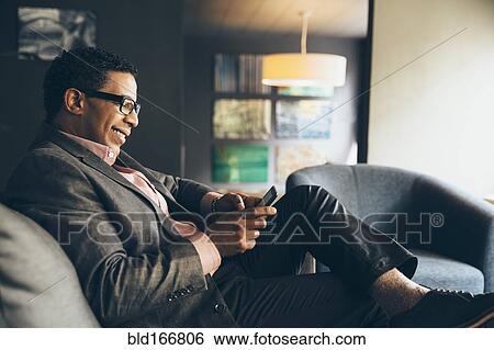 Stock Photograph - Mixed race businessman using digital tablet in office lobby. Fotosearch