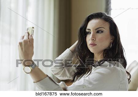 Stock Photography - Mixed race businesswoman checking her makeup in hotel lobby. Fotosearch