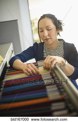 Mixed race businesswoman choosing files in office View Large Photo Image Stock Image - Mixed race businesswoman choosing files in office. Fotosearch