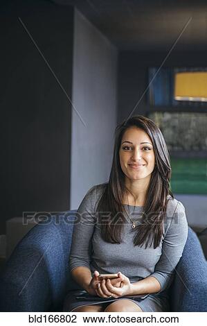 Stock Image - Mixed race businesswoman holding cell phone in office lobby. Fotosearch