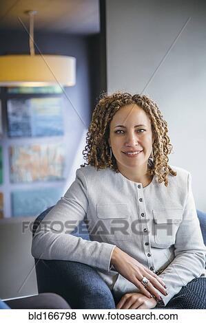 Stock Photo - Mixed race businesswoman smiling in office lobby. Fotosearch