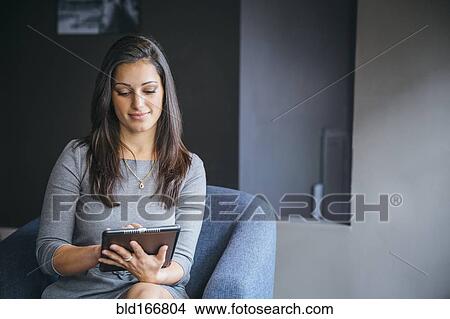 Picture - Mixed race businesswoman using digital tablet in office lobby. Fotosearch