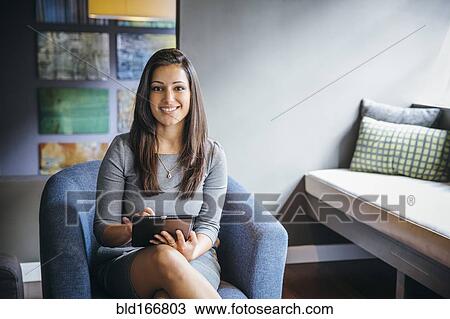 Stock Image - Mixed race businesswoman using digital tablet in office lobby. Fotosearch