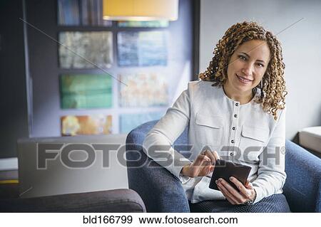 Stock Photo - Mixed race businesswoman using digital tablet in office lobby. Fotosearch