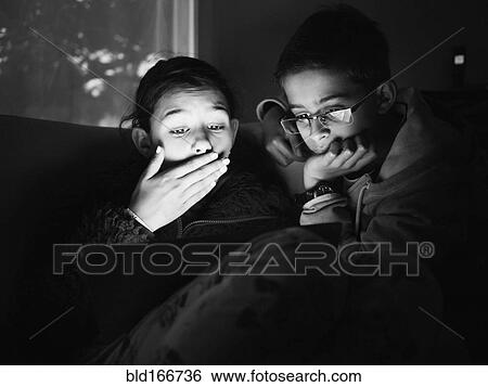 Stock Photograph - Mixed race children using digital tablet at night. Fotosearch