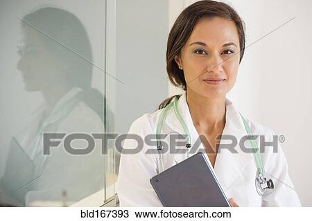 Stock Image - Mixed race doctor holding digital tablet. Fotosearch
