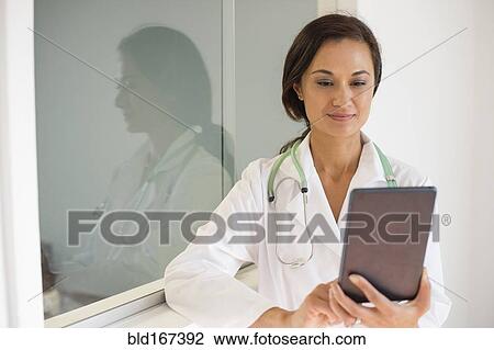 Stock Image - Mixed race doctor using digital tablet. Fotosearch