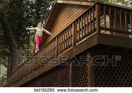 Mixed race girl balancing on balcony banister View Large Photo Image Stock Photography - Mixed race girl balancing on balcony banister. Fotosearch