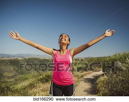 Stock Image - Mixed race girl cheering on hillside path. Fotosearch