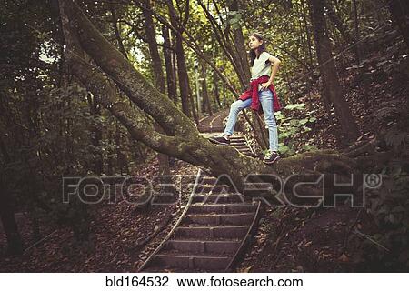 Stock Image - Mixed race girl exploring lush forest. Fotosearch