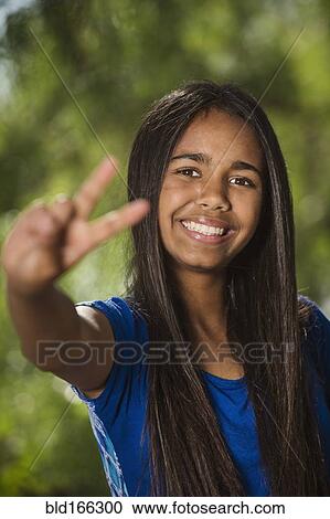 Stock Image - Mixed race girl giving peace sign. Fotosearch