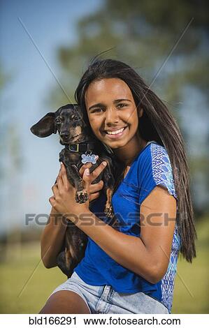 Stock Image - Mixed race girl hugging dog outdoors. Fotosearch
