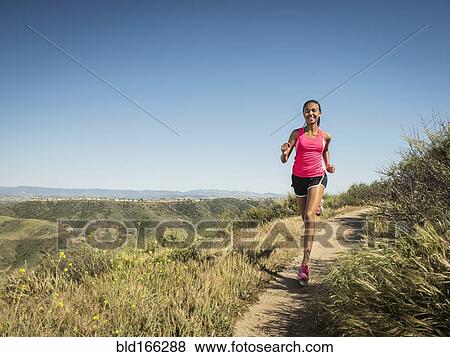 Stock Photo - Mixed race girl running on hillside path. Fotosearch