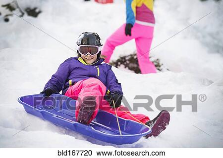 Mixed race girl sledding on snowy hillside View Large Photo Image Stock Image - Mixed race girl sledding on snowy hillside. Fotosearch