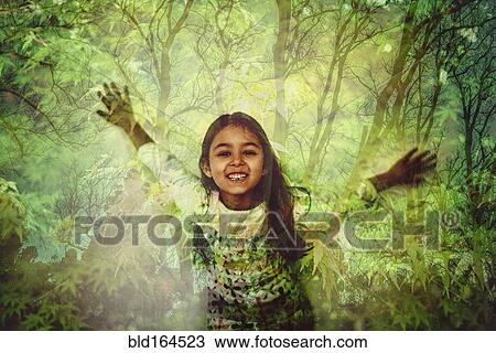 Stock Image - Mixed race girl standing in forest projection. Fotosearch