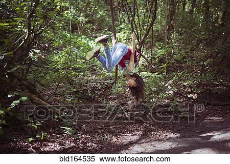Mixed race girl swinging from tree branch on dirt path View Large Photo Image Stock Photography - Mixed race girl swinging from tree branch on dirt path. Fotosearch