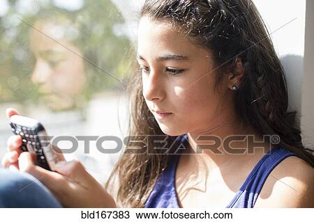 Mixed race girl using cell phone at window View Large Photo Image Stock Image - Mixed race girl using cell phone at window. Fotosearch